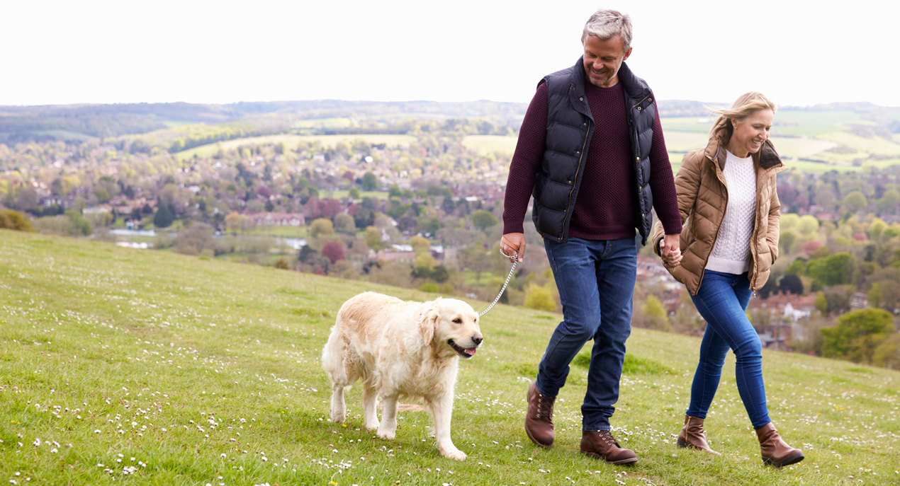 Couple walking their dog on a hill wearing coats