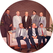 group of executives, three people are sitting on a couch, and five people are standing behind the couch