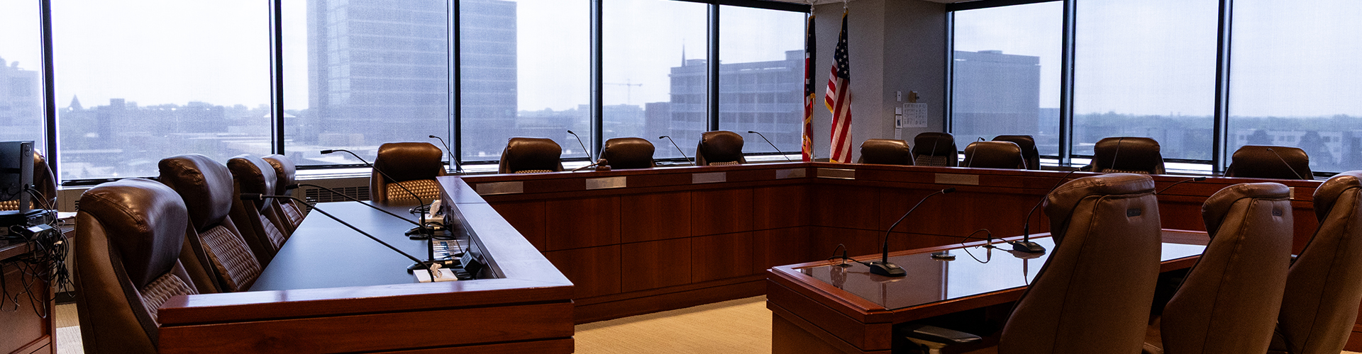 Brown conference desks with brown chairs and an American flag with the skyline on the background